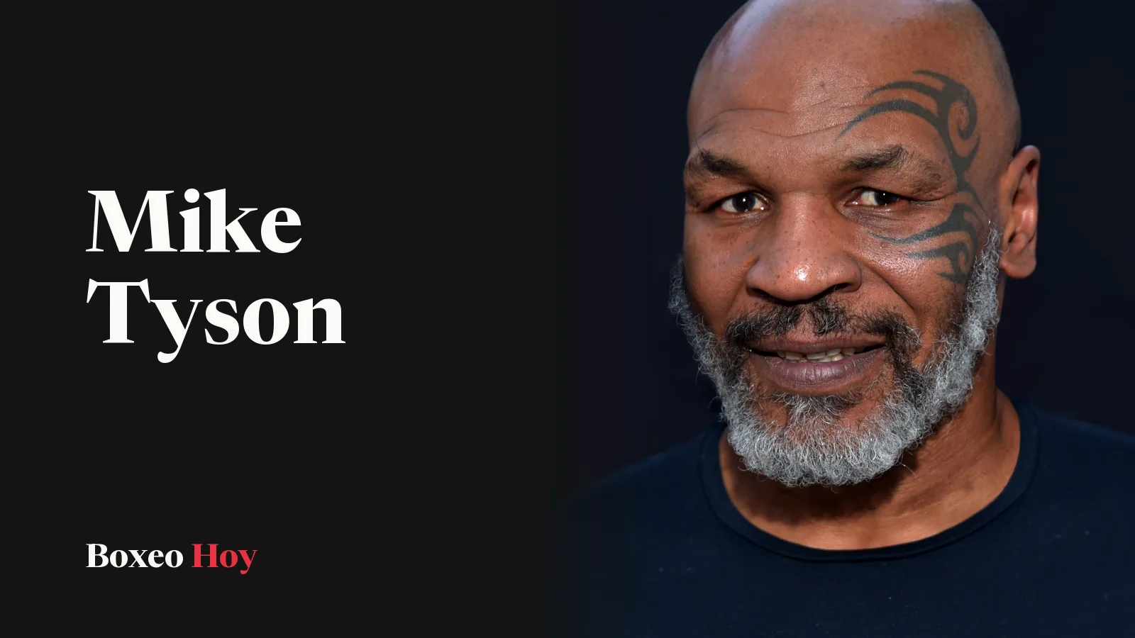 Mike Tyson sonríe en un retrato de 2019, con barba canosa, el tatuaje tribal junto al ojo izquierdo y camiseta negra